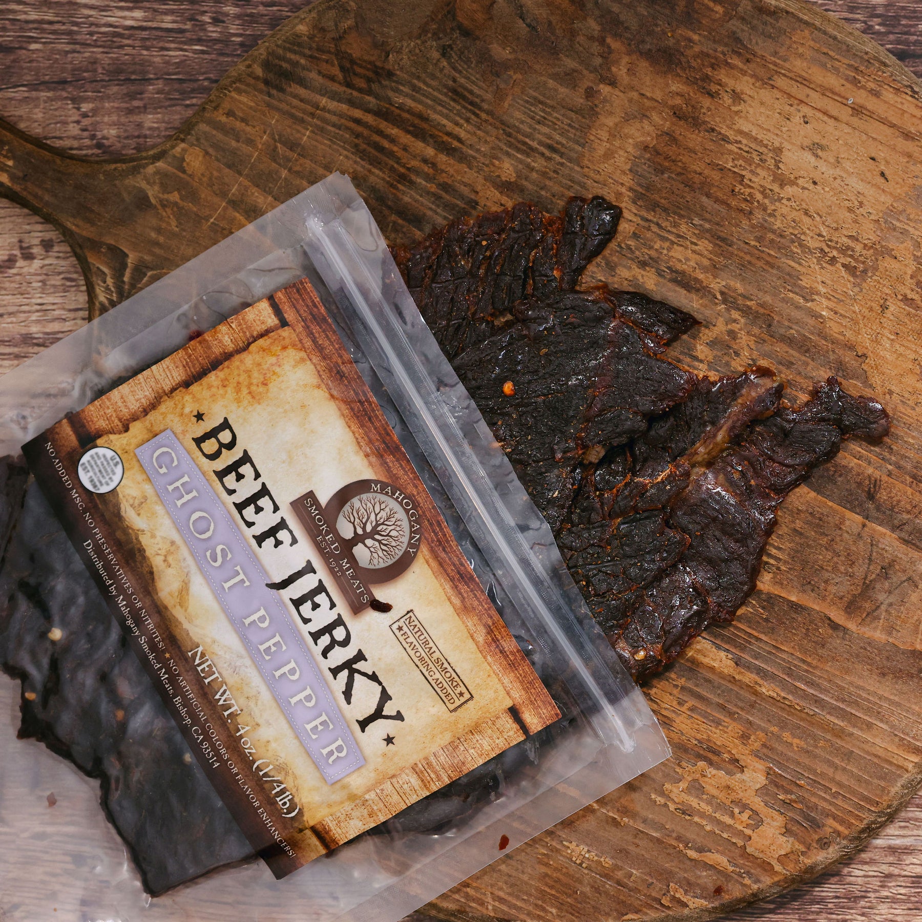 Open package of beef jerky labeled 'Ghost Pepper' on a wooden cutting board.