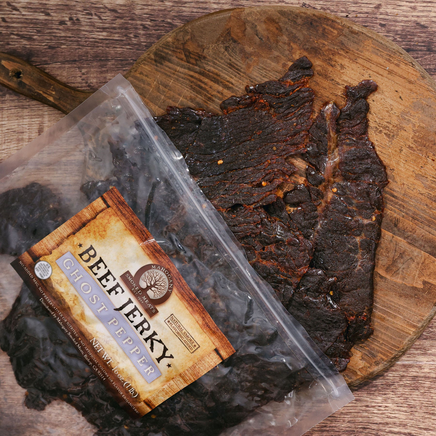 Ghost pepper beef jerky on a wooden cutting board, beside its packaging.