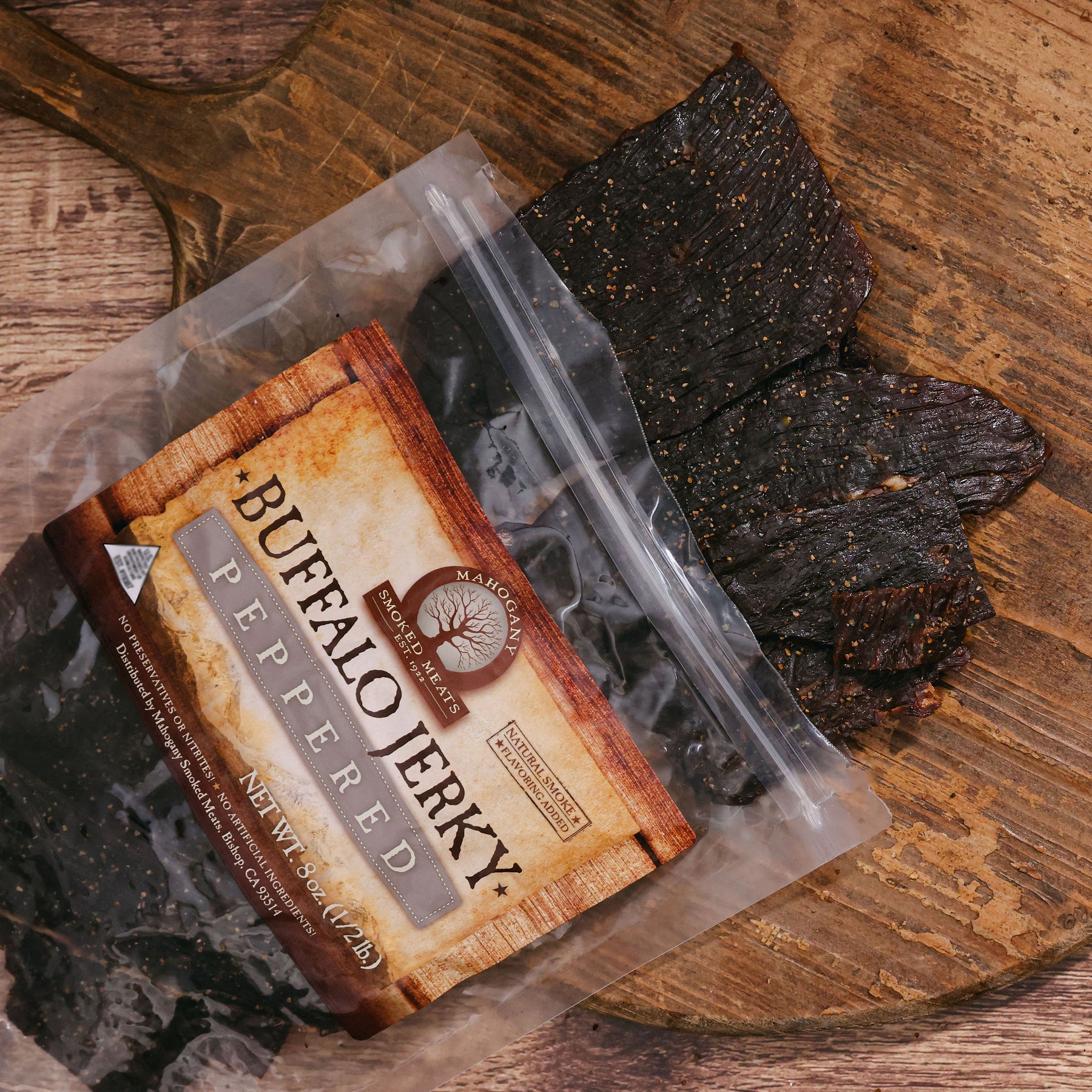 Black peppered buffalo jerky in an open package on a wooden surface.