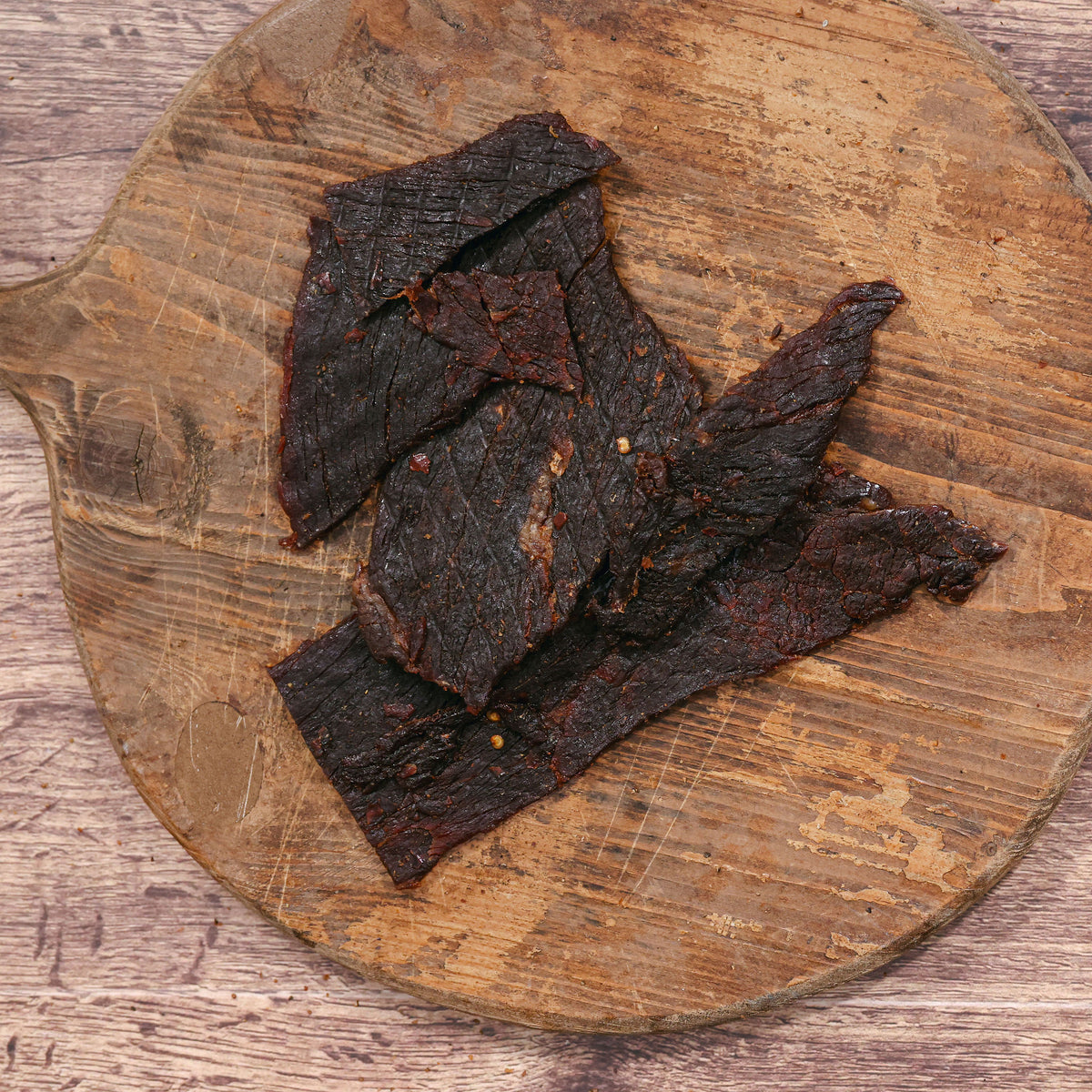 Dark habanero buffalo jerky strips on a rustic wooden cutting board.