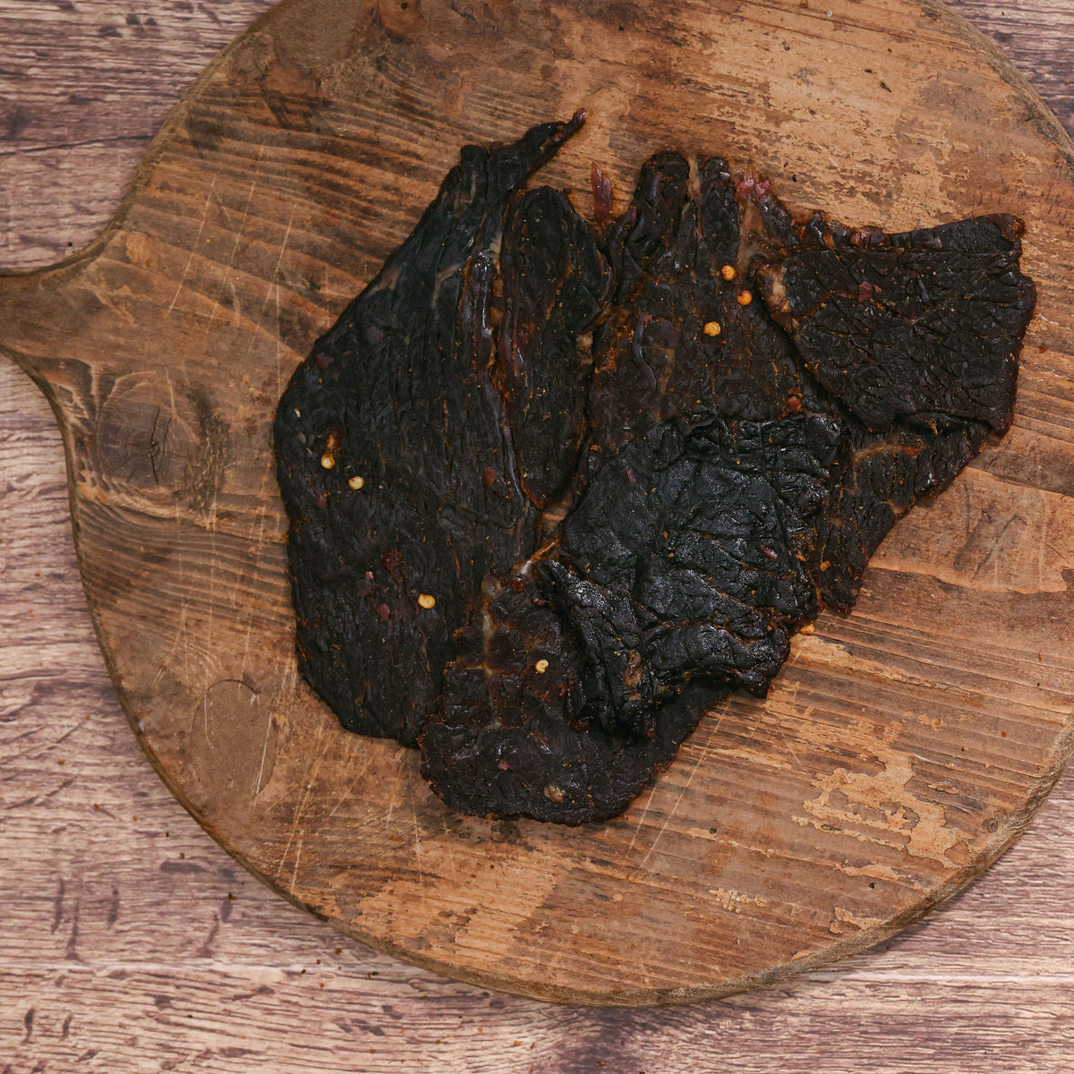 Dark habanero beef jerky pieces on a rustic wooden board.