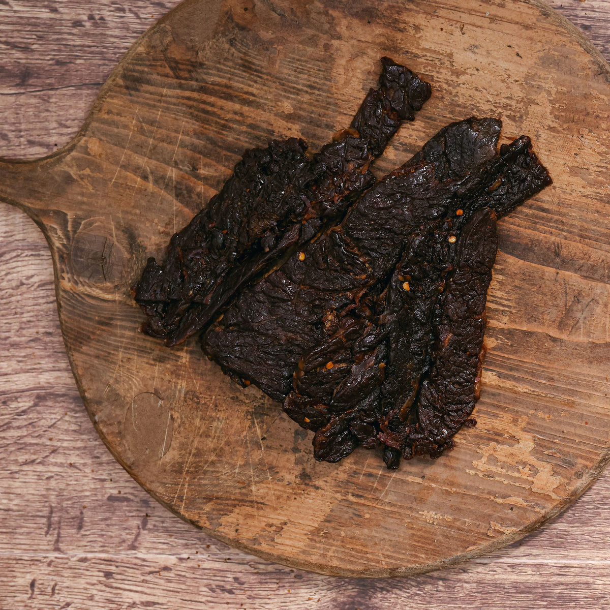 Habanero brisket jerky strips on a rustic wooden cutting board.