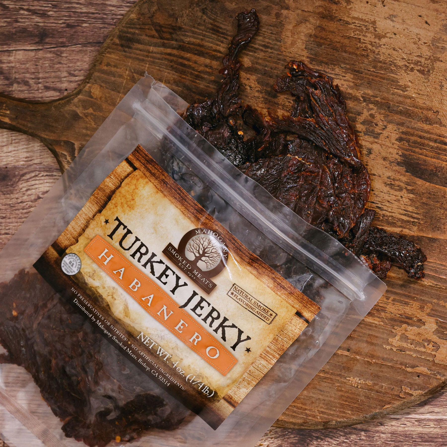 Packaged habanero turkey jerky on wooden surface, partially out of the open bag.