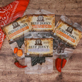 Assorted spicy jerky packs with habanero and ghost pepper on a wooden table, flanked by chili peppers.