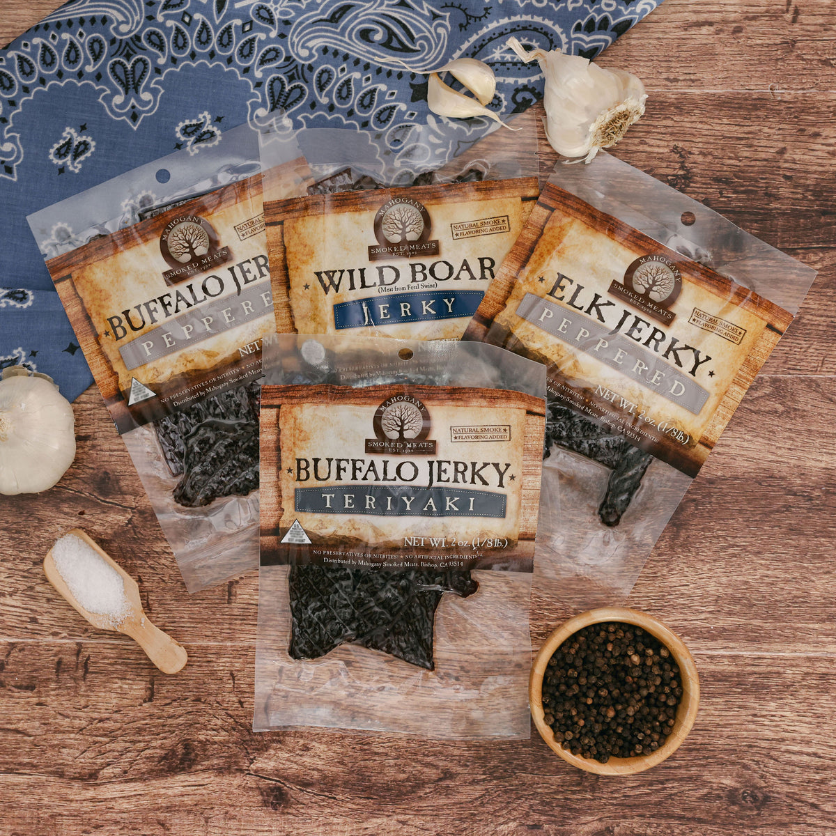 Assorted exotic jerky packets including buffalo, wild boar, and elk on a wooden surface with spices.