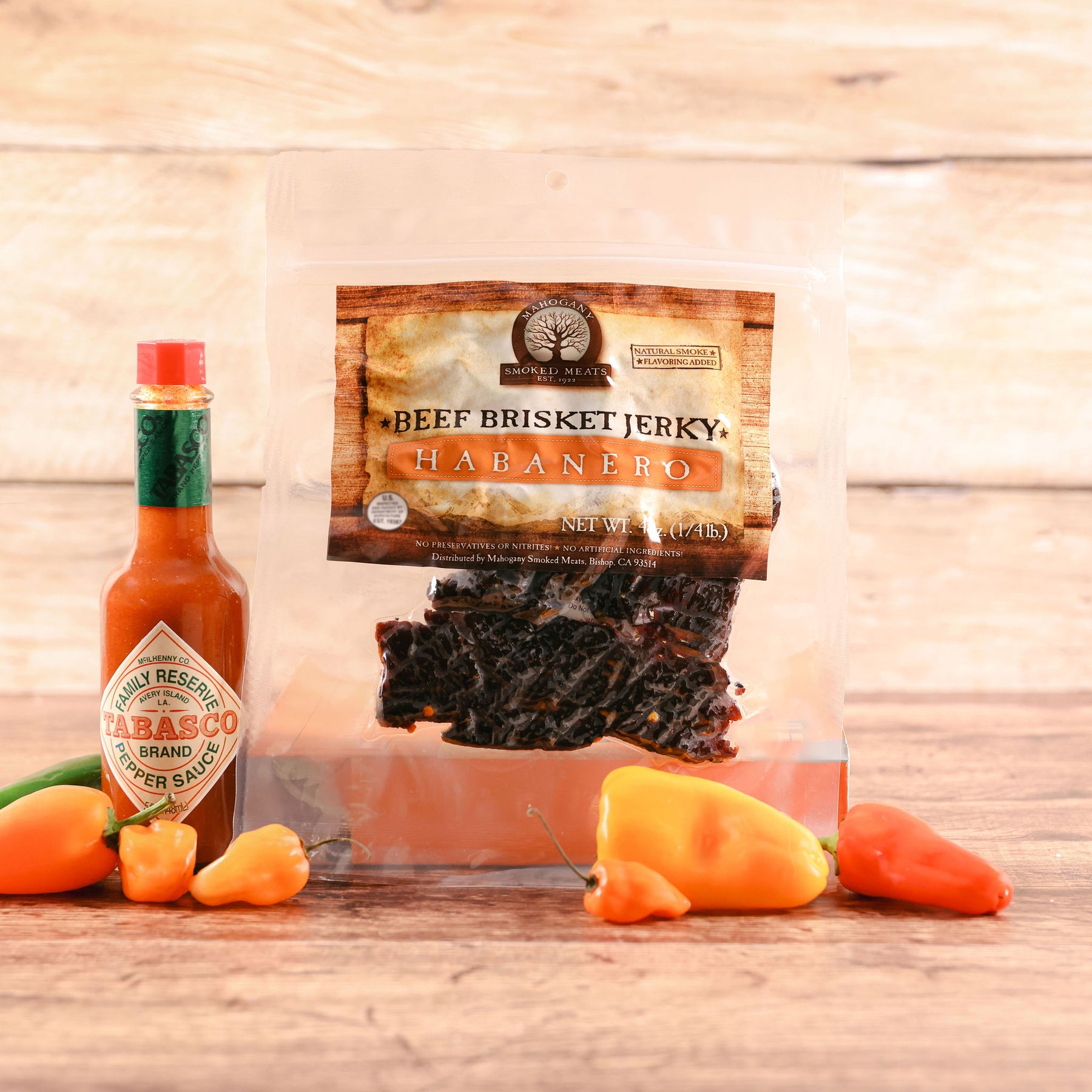 Packaged beef brisket jerky labeled "Habanero" next to a Tabasco sauce bottle and fresh peppers.
