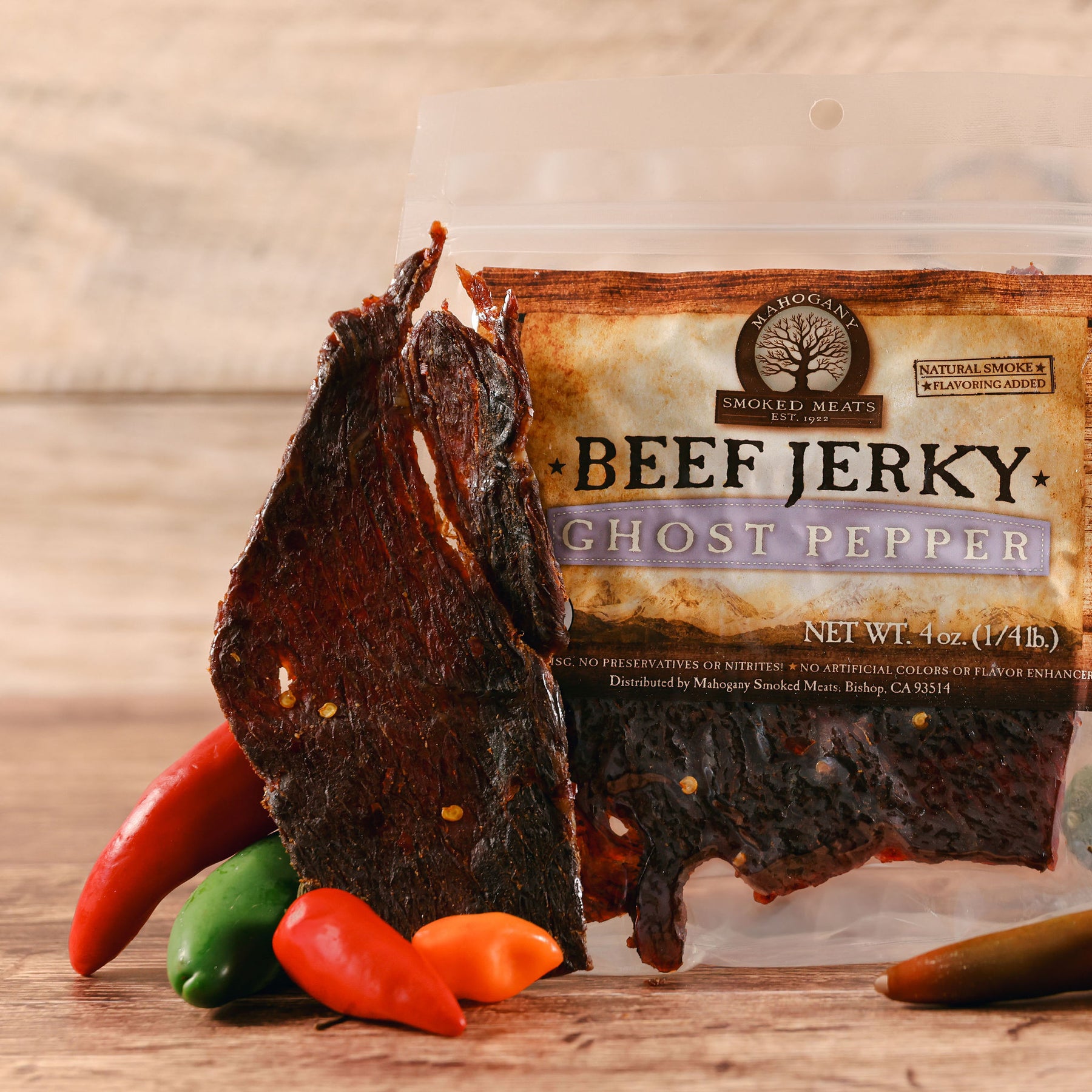 Beef jerky flavored with ghost pepper displayed next to multicolored chili peppers