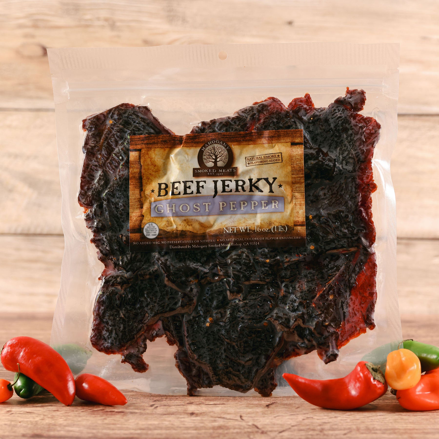 Packaged ghost pepper beef jerky with colorful chili peppers on a wooden surface