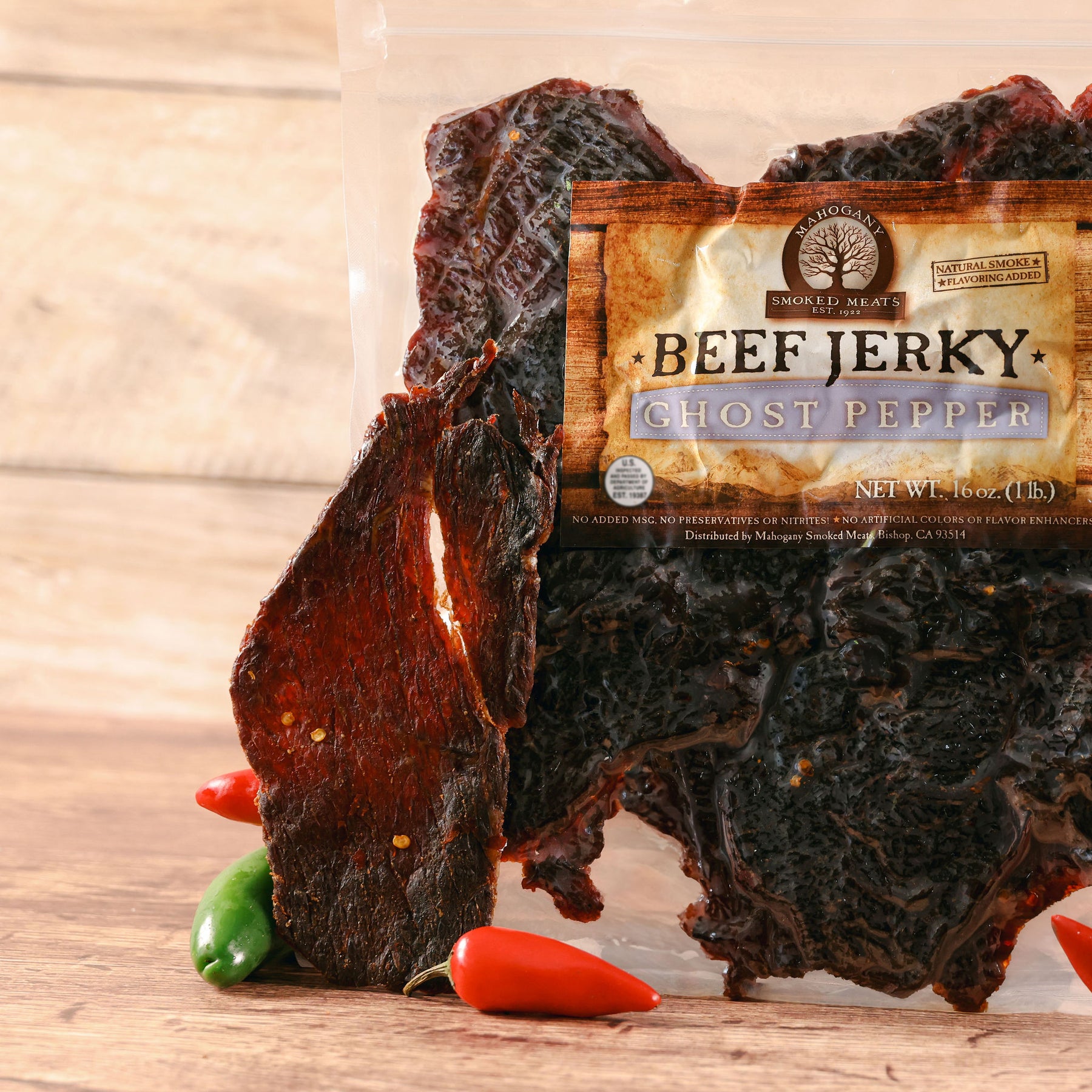 Ghost pepper beef jerky displayed with fresh peppers on wooden surface