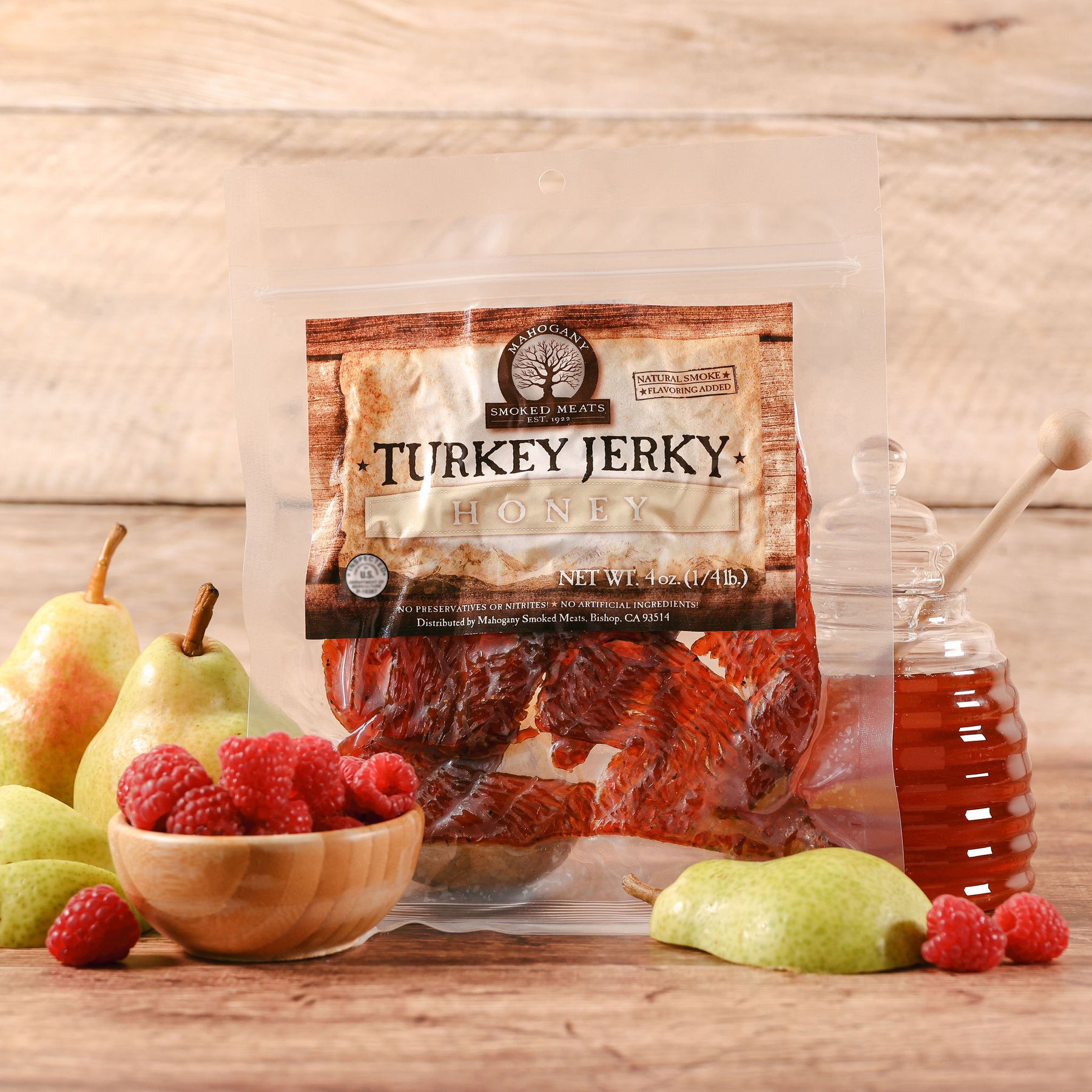 Package of honey turkey jerky with fruits and honey jar on a wooden surface