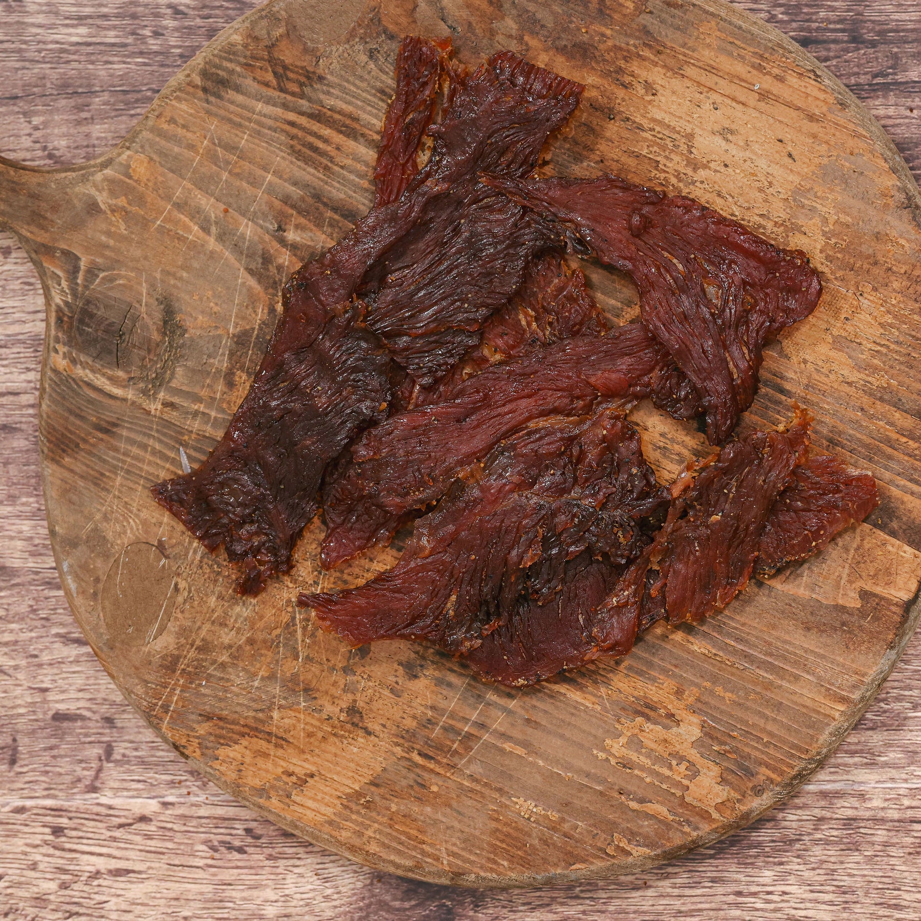 Slices of honey turkey jerky on a rustic wooden cutting board.