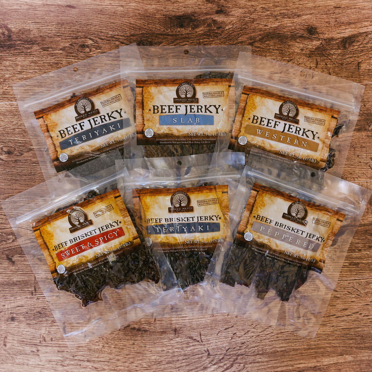 Six packets of various flavored beef jerky displayed on a wooden surface