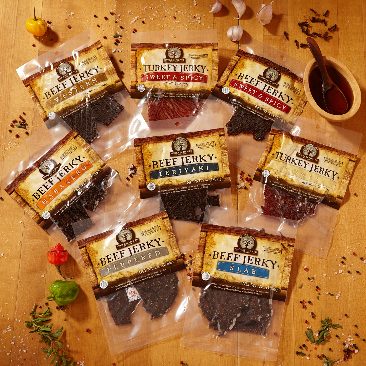 Assorted beef and turkey jerky packs on a wooden surface with spices and sauce.