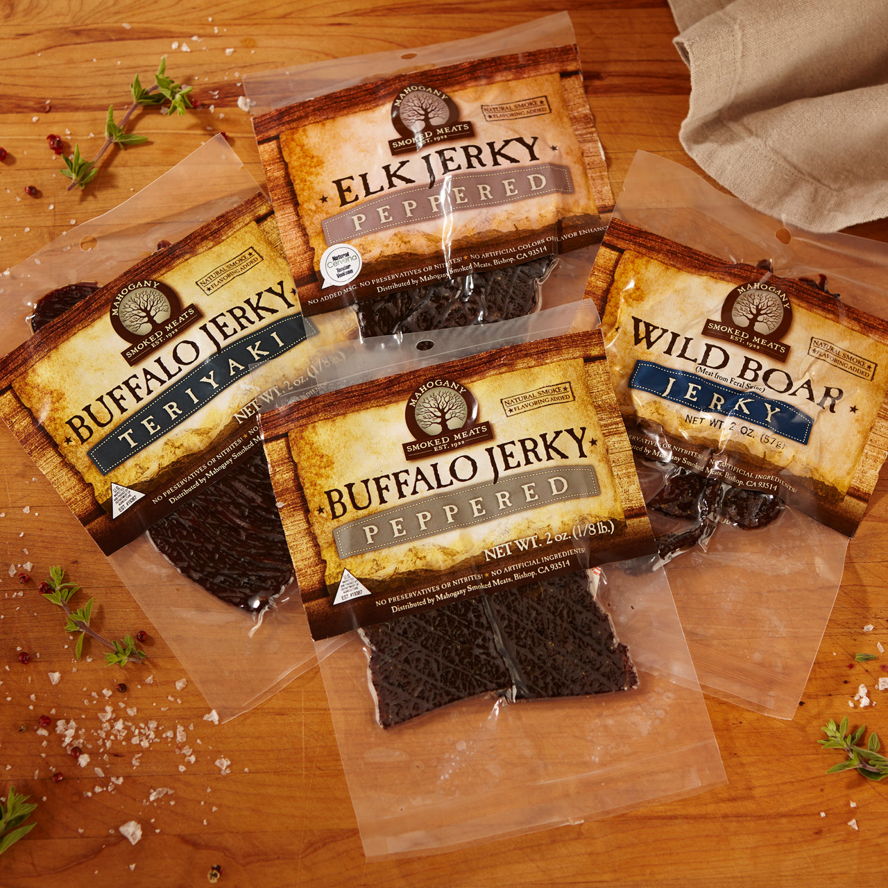 Assortment of exotic jerky packages including elk, buffalo, and wild boar on a wooden surface.