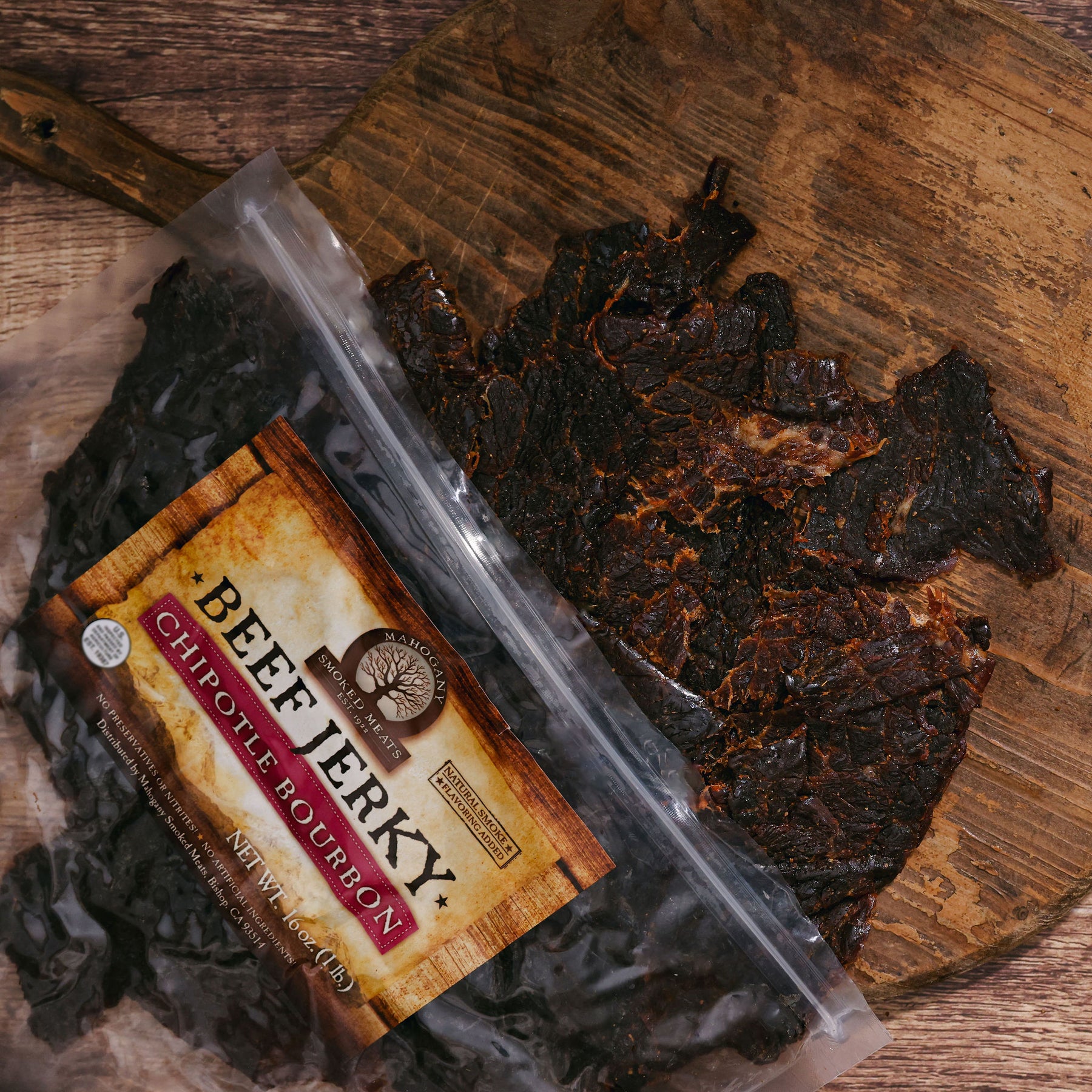 Packaged Chipotle Bourbon Beef Jerky on a rustic wooden board.