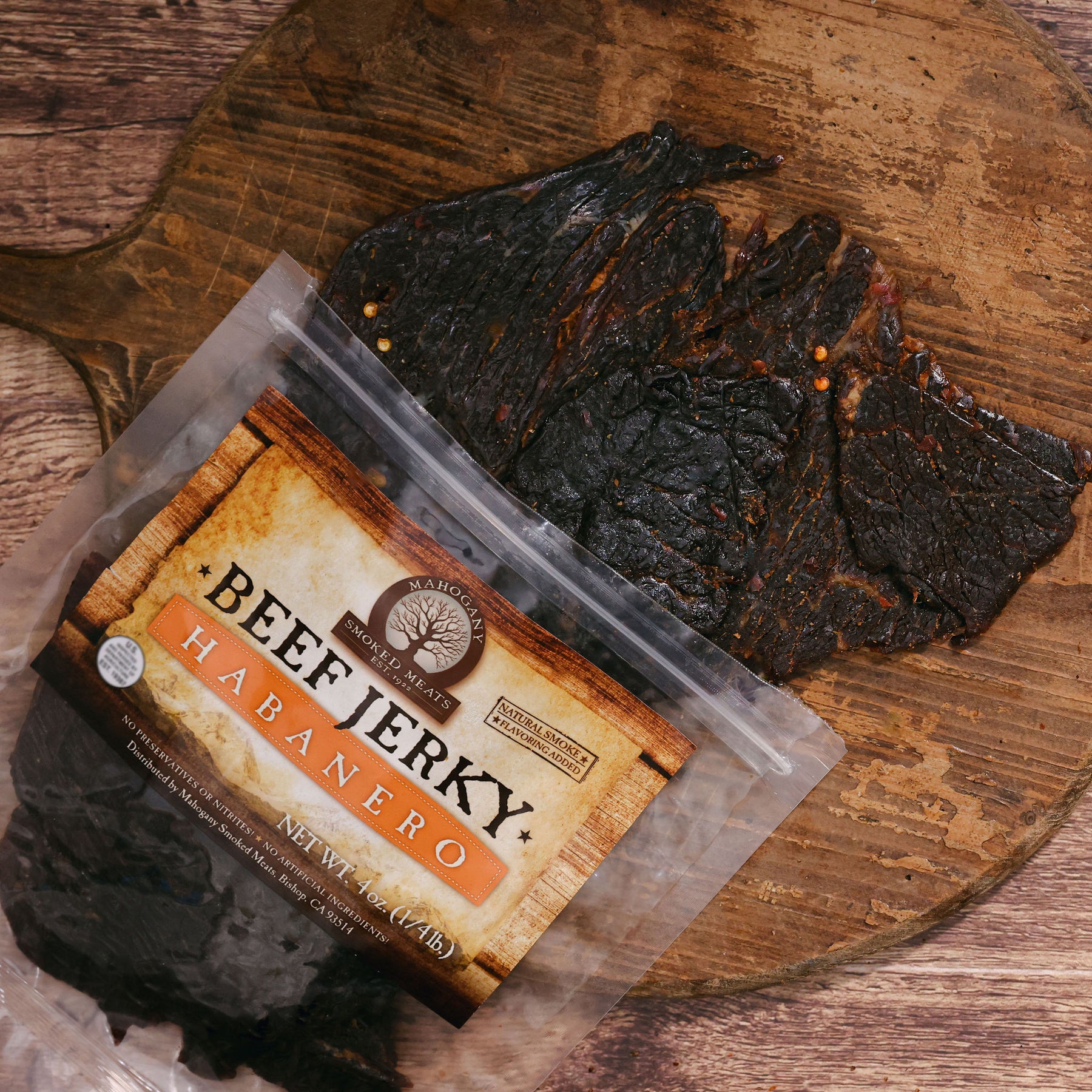 Habanero beef jerky on a wooden board beside its packaging with vibrant label.