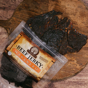 Habanero beef jerky on a wooden board beside its packaging with vibrant label.