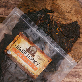 Transparent package of habanero beef jerky on a wooden board, showing dark spicy meat slices.