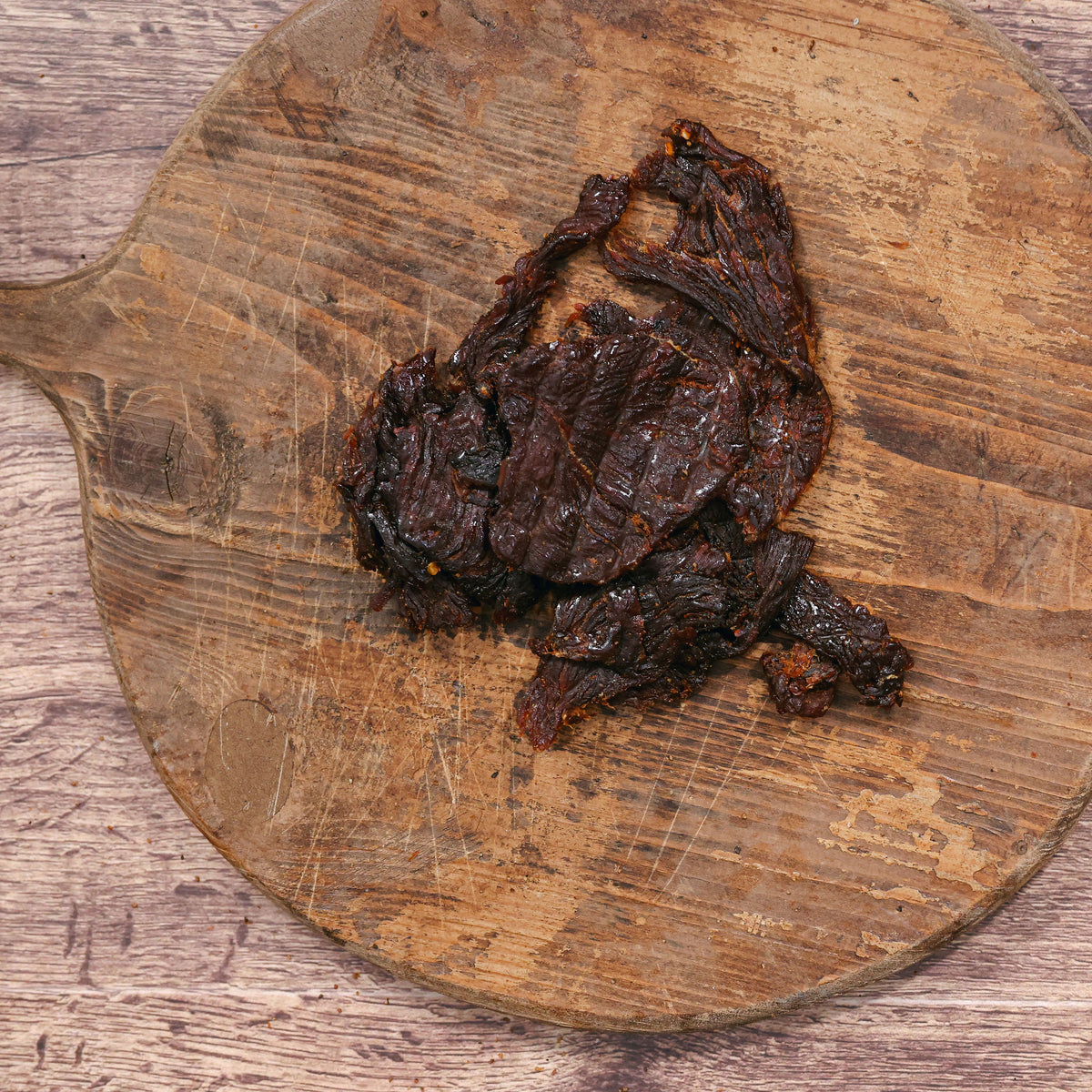 Dark habanero turkey jerky on a rustic wooden cutting board.