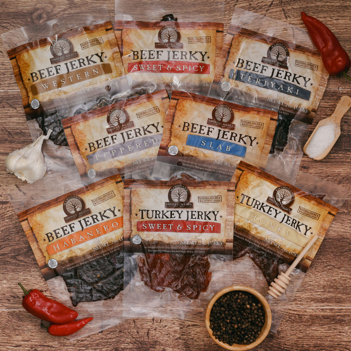 Assortment of jerky packs labeled sweet & spicy, teriyaki, and slab, surrounded by spices and garlic.
