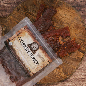 Honey turkey jerky on a rustic wooden board with open packaging